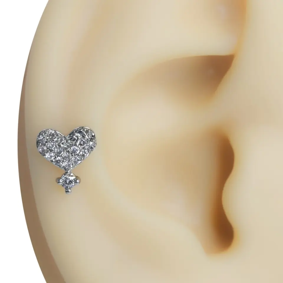Kulak üzerinde sergilenen gümüş renkli ağlayan kalp formunda zirkon taşlı tragus helix kıkırdak piercing