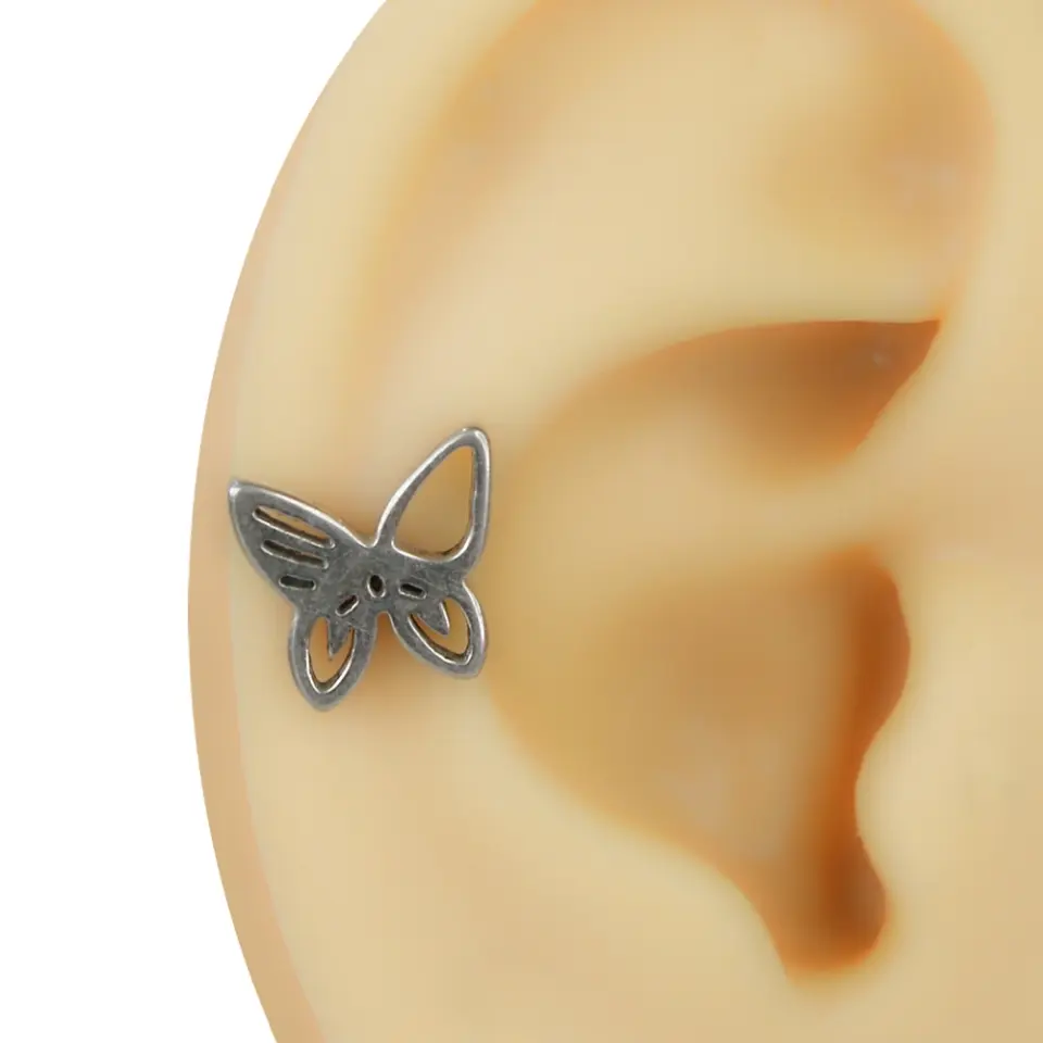 Kulakta helix bölgesinde takılı gümüş renkli içi boş kelebek figürlü flatback piercing