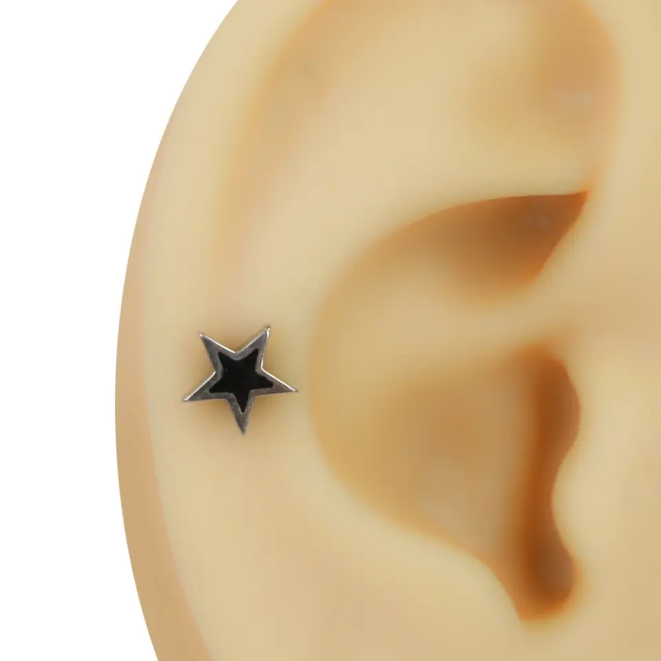 Kulakta lobe bölgesinde takılı gümüş renk çerçeveli siyah yıldız figürlü tünel görünümlü piercing