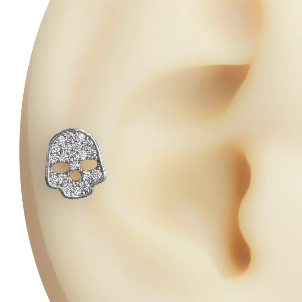 Kulak kıkırdağında sergilenen zirkon taşlı kurukafa figürlü tragus helix kıkırdak piercing